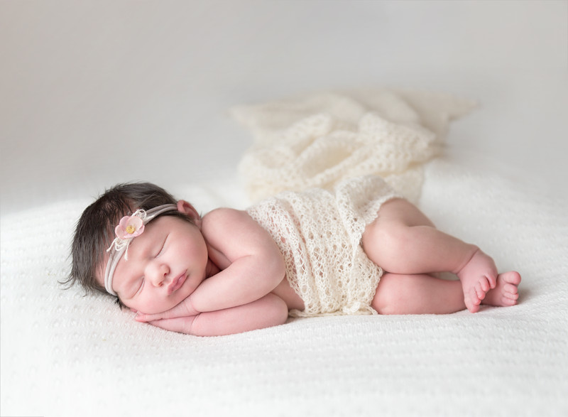 Newborn in lace blanket with flower headband